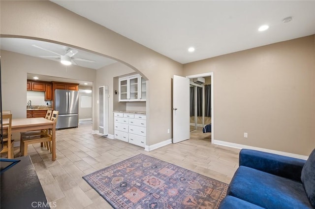 living area with a ceiling fan, recessed lighting, arched walkways, and baseboards