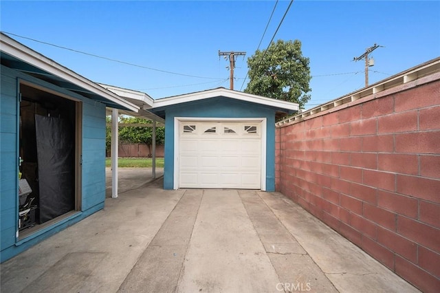 garage featuring fence and concrete driveway