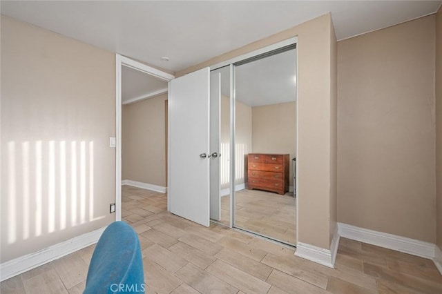 interior space featuring wood tiled floor, a closet, and baseboards