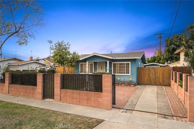 bungalow with a fenced front yard, a gate, and stucco siding