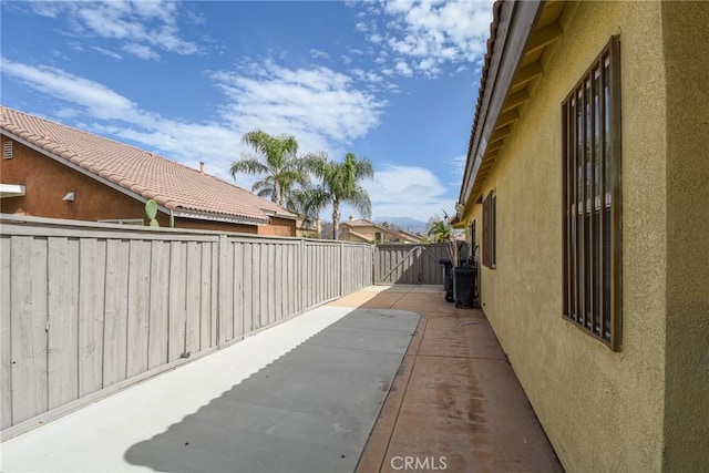 exterior space with a patio area, a fenced backyard, a tile roof, and stucco siding