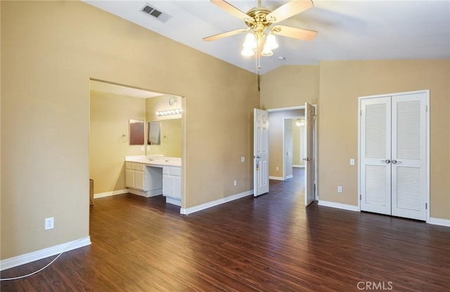 unfurnished bedroom with lofted ceiling, dark wood-style flooring, visible vents, baseboards, and a closet