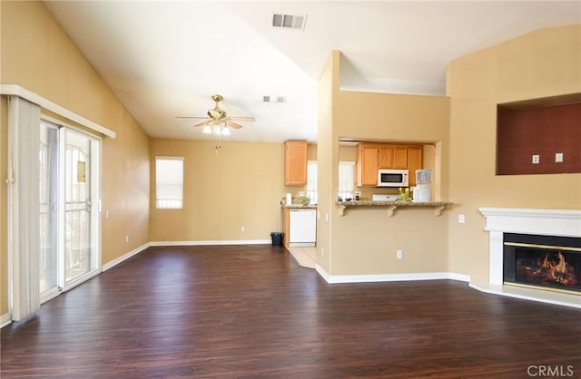 unfurnished living room featuring dark wood finished floors, visible vents, a ceiling fan, a glass covered fireplace, and vaulted ceiling