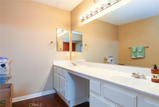 bathroom featuring double vanity, baseboards, a sink, and wood finished floors