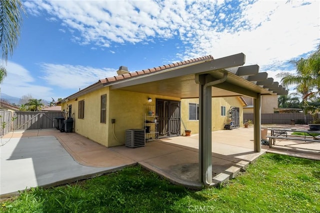 rear view of house featuring a patio, central air condition unit, fence, and stucco siding