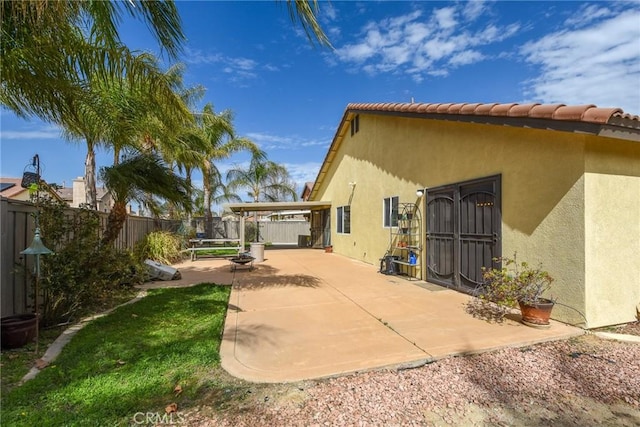 view of side of property featuring a fenced backyard, a tile roof, stucco siding, a trampoline, and a patio area