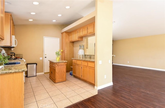 kitchen with vaulted ceiling, a kitchen island, baseboards, and white microwave