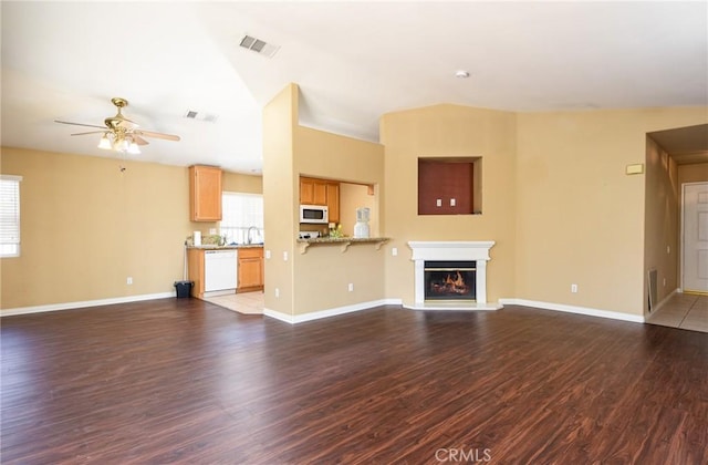 unfurnished living room with a glass covered fireplace, visible vents, plenty of natural light, and wood finished floors