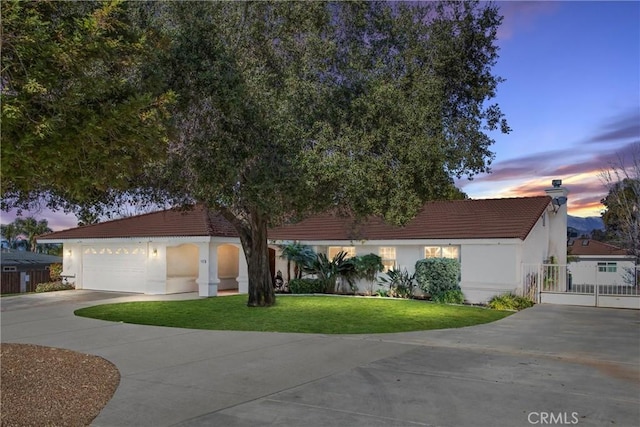 view of front of property featuring a tile roof, stucco siding, an attached garage, a front yard, and driveway