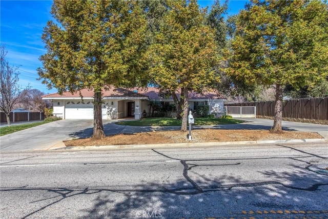 view of front facade featuring an attached garage, fence, concrete driveway, and stucco siding