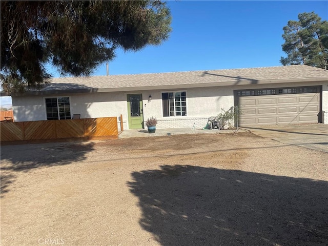 single story home with a garage, brick siding, a shingled roof, driveway, and stucco siding