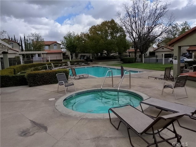 community pool with a patio, a community hot tub, and fence