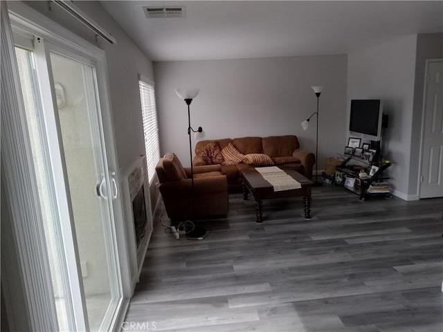 living area featuring visible vents, baseboards, and wood finished floors