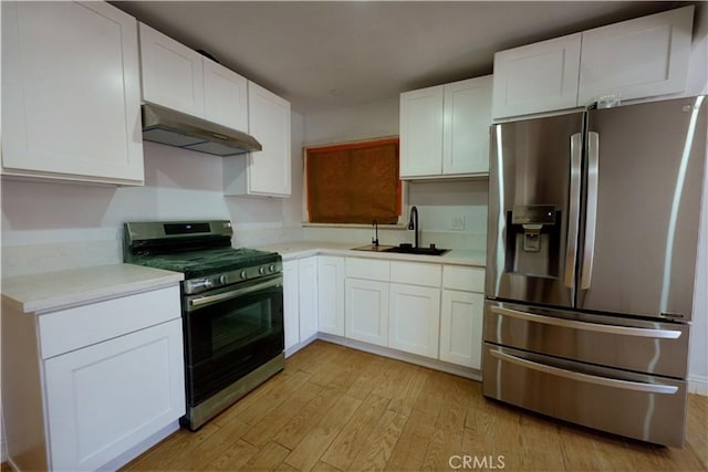 kitchen with under cabinet range hood, a sink, white cabinets, light countertops, and appliances with stainless steel finishes