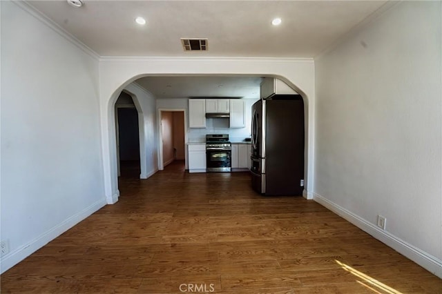 hallway featuring arched walkways, visible vents, crown molding, and dark wood-style floors