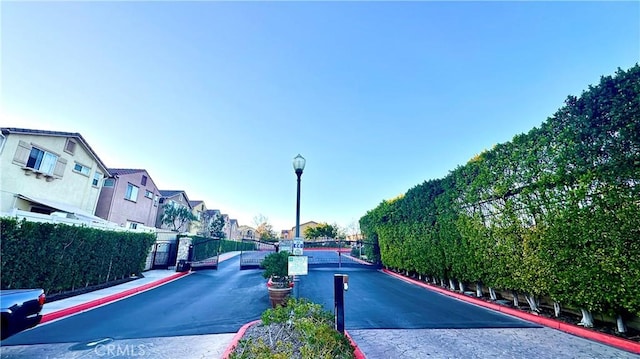 view of street featuring street lighting, a residential view, a gated entry, curbs, and sidewalks