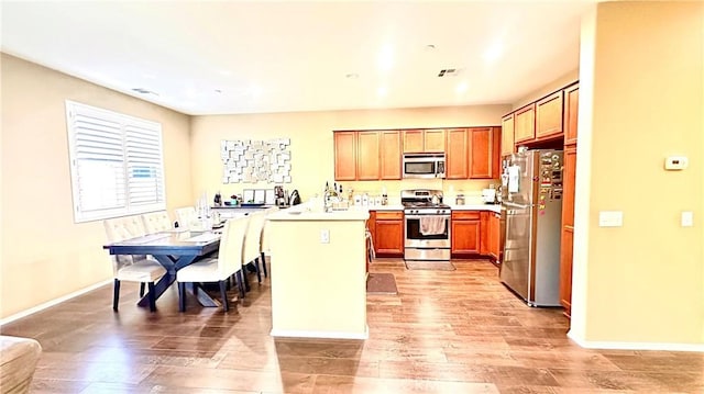 kitchen with stainless steel appliances, light countertops, light wood-style flooring, a peninsula, and baseboards