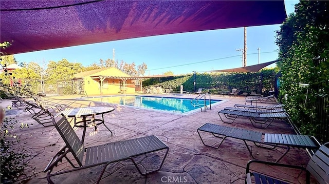 community pool with fence and a patio