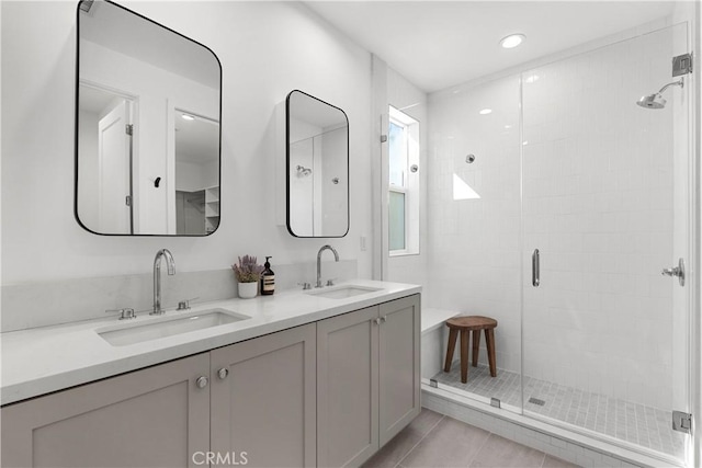 full bath featuring a shower stall, double vanity, tile patterned floors, and a sink