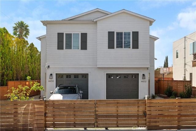 view of front of property featuring a fenced front yard, driveway, an attached garage, and stucco siding