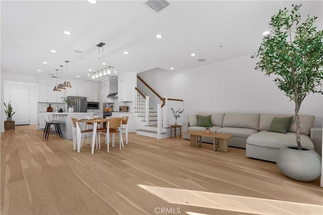 living area featuring stairway, recessed lighting, light wood-style flooring, and visible vents