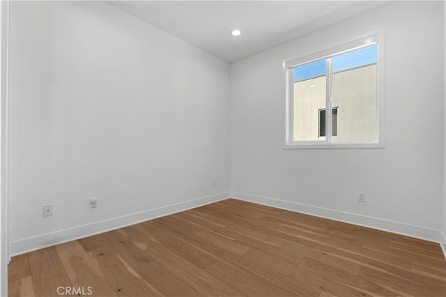 spare room featuring recessed lighting, light wood-type flooring, and baseboards