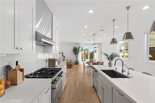 kitchen with a sink, stainless steel appliances, light wood-style flooring, and light countertops