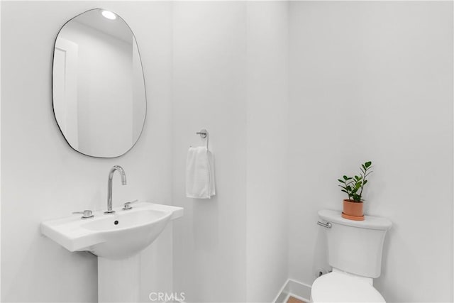 bathroom featuring toilet, baseboards, and a sink