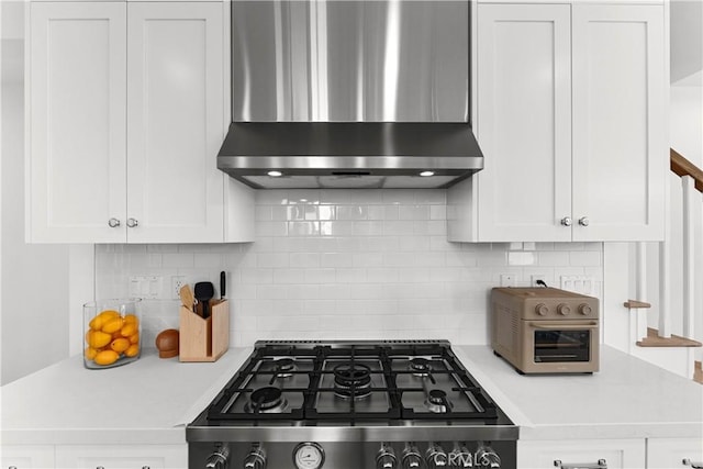 kitchen with white cabinets, light countertops, wall chimney range hood, and range