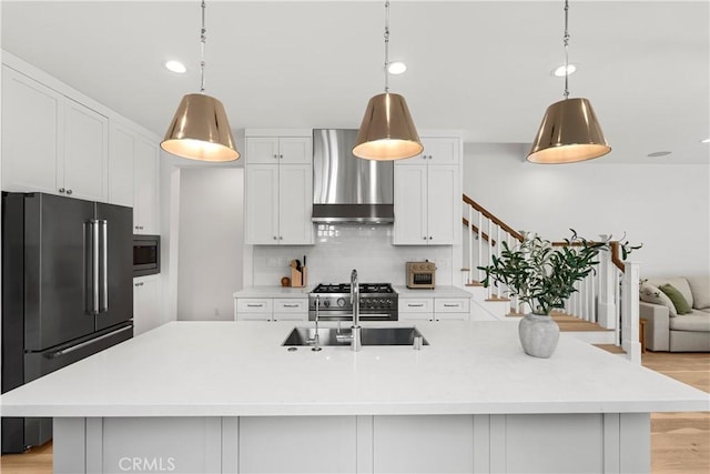 kitchen featuring a sink, decorative backsplash, stainless steel microwave, wall chimney exhaust hood, and high quality fridge