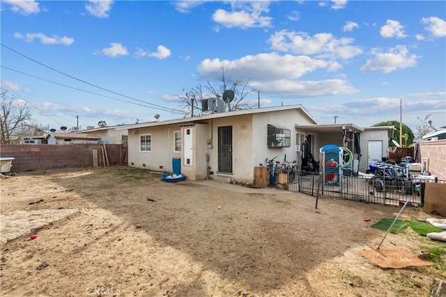 rear view of property with central AC, a fenced backyard, and stucco siding