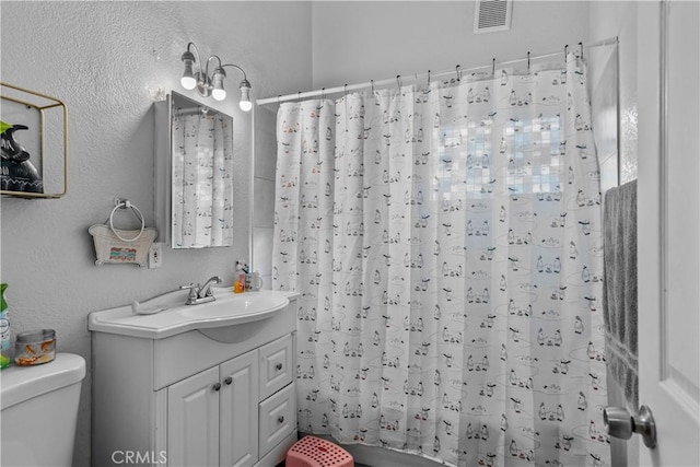 bathroom with visible vents, a textured wall, vanity, and toilet