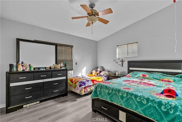 bedroom with lofted ceiling, light wood-style flooring, and a ceiling fan