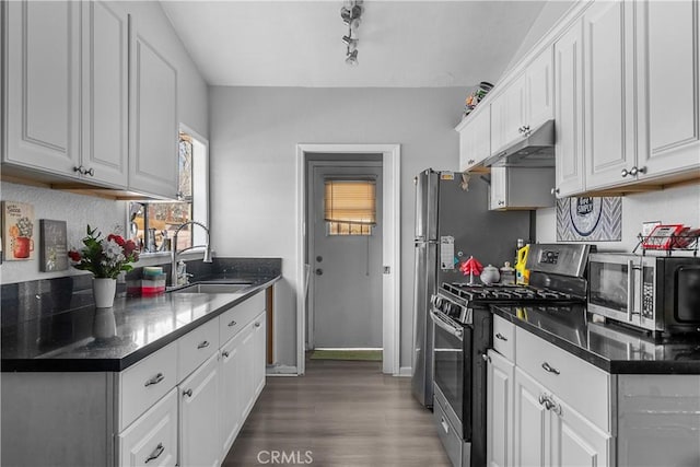 kitchen with white cabinets, dark countertops, stainless steel appliances, and a sink