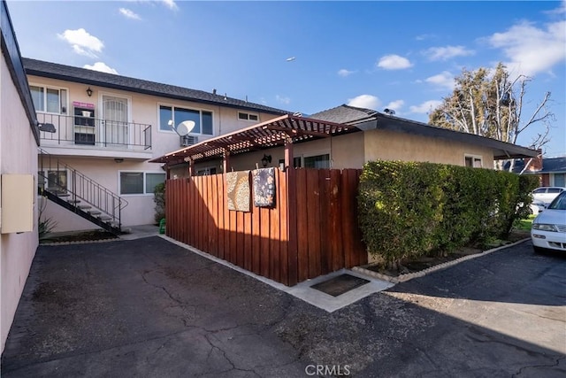 view of side of property with stairway, fence, and stucco siding