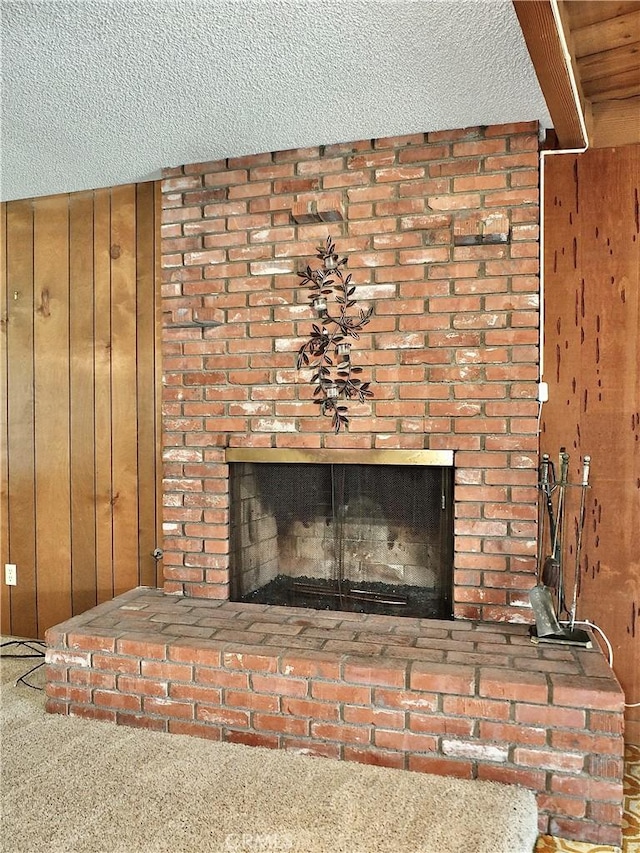 room details featuring a brick fireplace, wood walls, and a textured ceiling