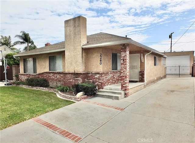 single story home with stucco siding, driveway, a front yard, brick siding, and a chimney