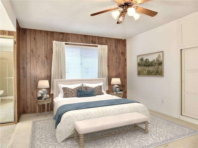 bedroom featuring a textured ceiling, wooden walls, a ceiling fan, and light carpet