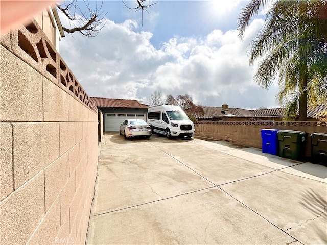 view of parking featuring driveway, a garage, and fence