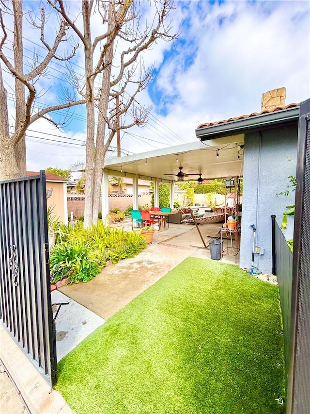 view of yard with a patio area, fence, and a ceiling fan