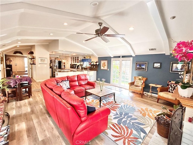 living room featuring light wood finished floors, lofted ceiling, visible vents, a ceiling fan, and baseboards