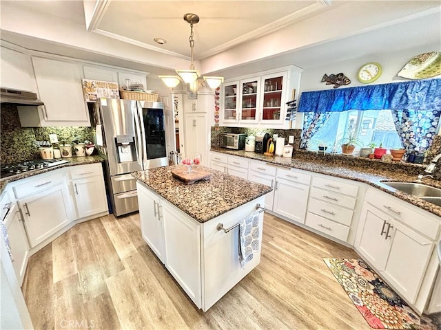 kitchen with white cabinets, light wood-style flooring, stainless steel appliances, and a sink