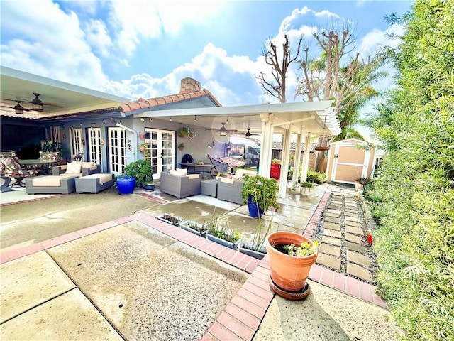 rear view of property with a patio, outdoor lounge area, an outdoor structure, french doors, and a storage unit