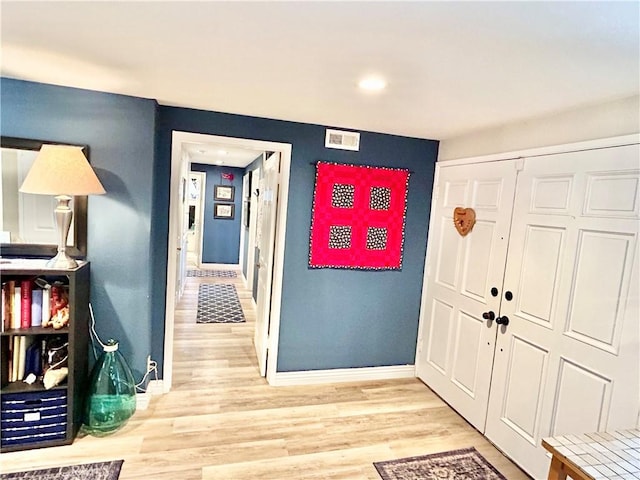 foyer entrance featuring light wood-type flooring, visible vents, and baseboards