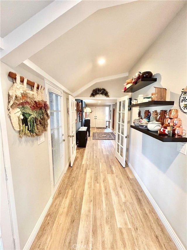 hallway with lofted ceiling, french doors, light wood-style flooring, and baseboards