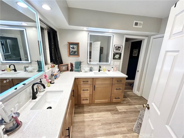 full bath featuring visible vents, a sink, and wood finished floors