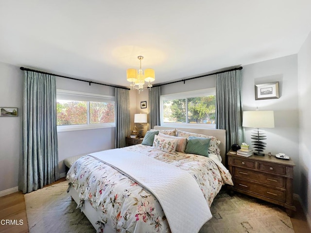 bedroom featuring baseboards, light wood finished floors, and a notable chandelier