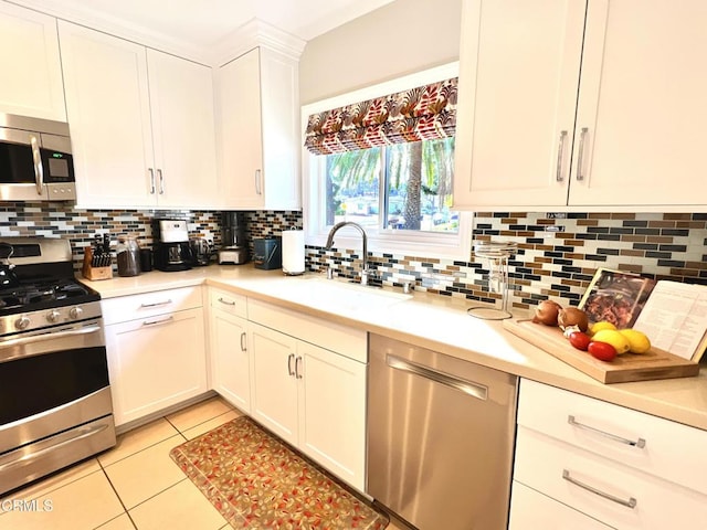 kitchen with backsplash, light countertops, stainless steel appliances, a sink, and light tile patterned flooring