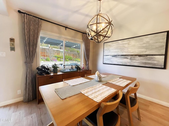 dining room featuring baseboards, a notable chandelier, and light wood finished floors