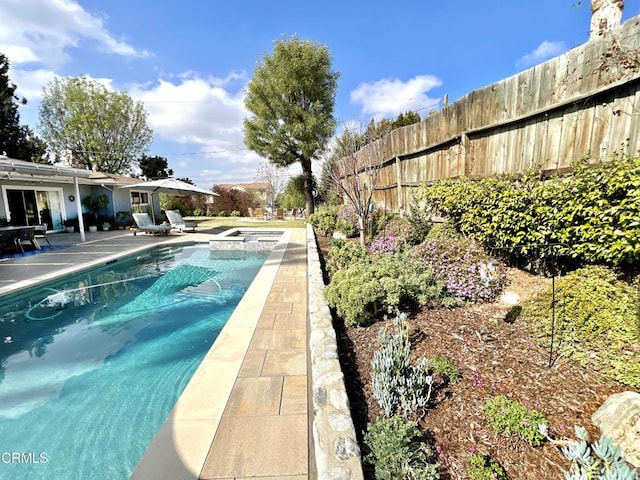 view of swimming pool featuring a patio area, fence, and a pool with connected hot tub